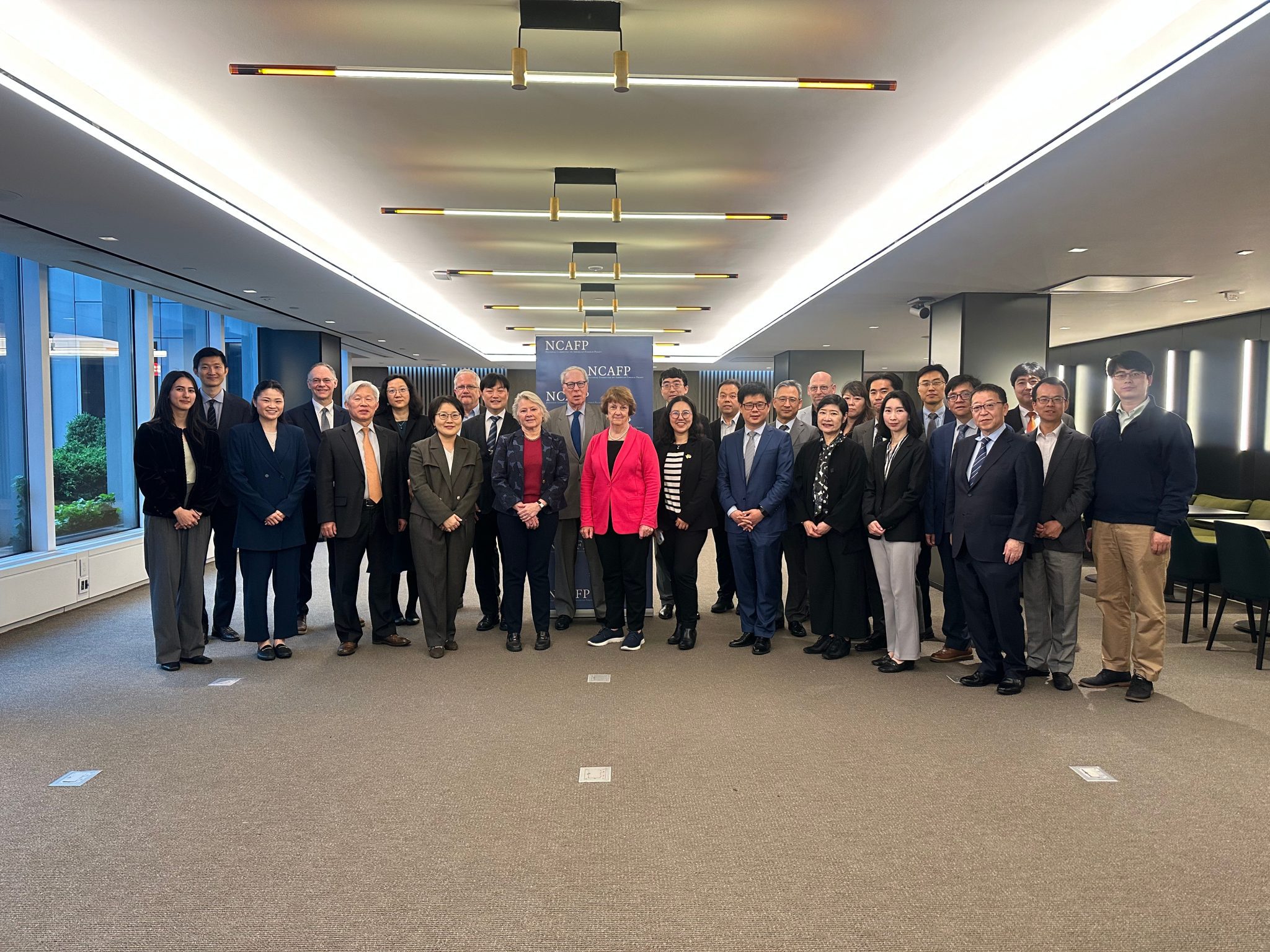 The group of policy experts and scholars stand in two rows.